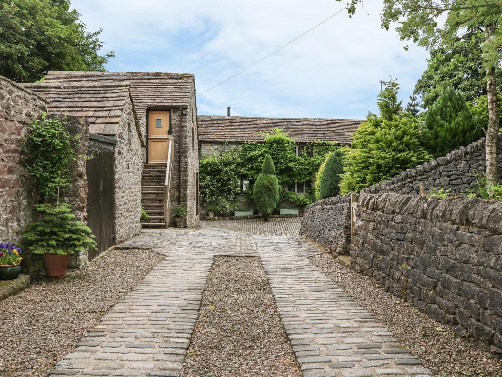 um caminho de pedra que leva a uma casa com uma parede de pedra em Barn Cottage em Buxton