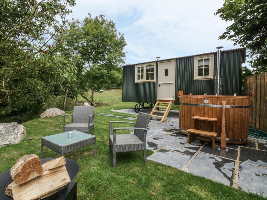 a tiny house in a yard with chairs and a table at Orchard in Wadebridge