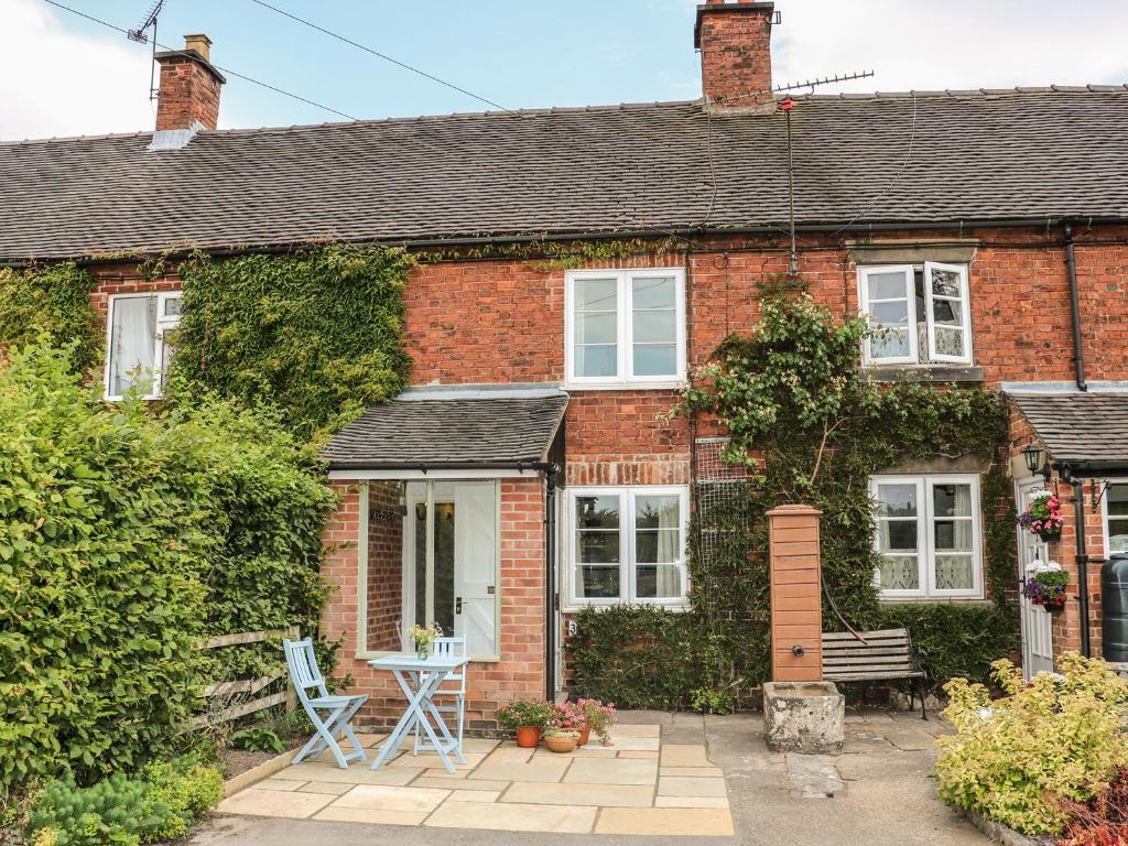 uma casa de tijolos com uma mesa e cadeiras em frente em Callow Cottages em Ashbourne