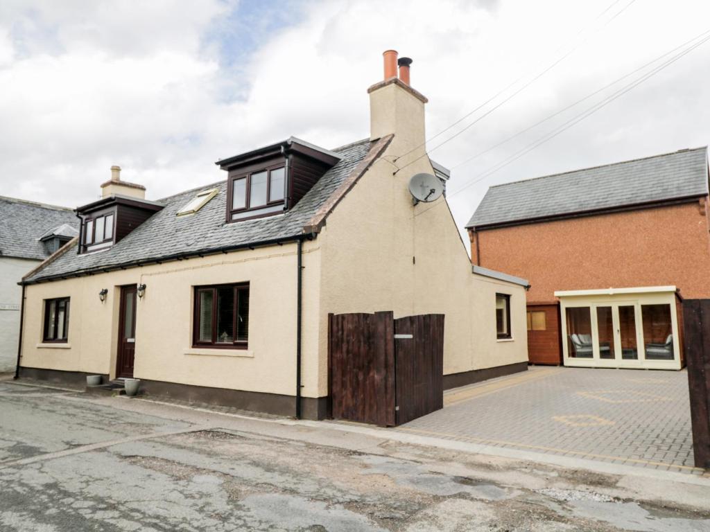 una vieja casa blanca con techo negro en Maclean Cottage, en Beauly