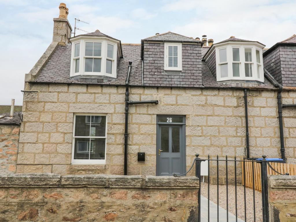 a stone house with a grey door and white windows at Westwood in Ballater