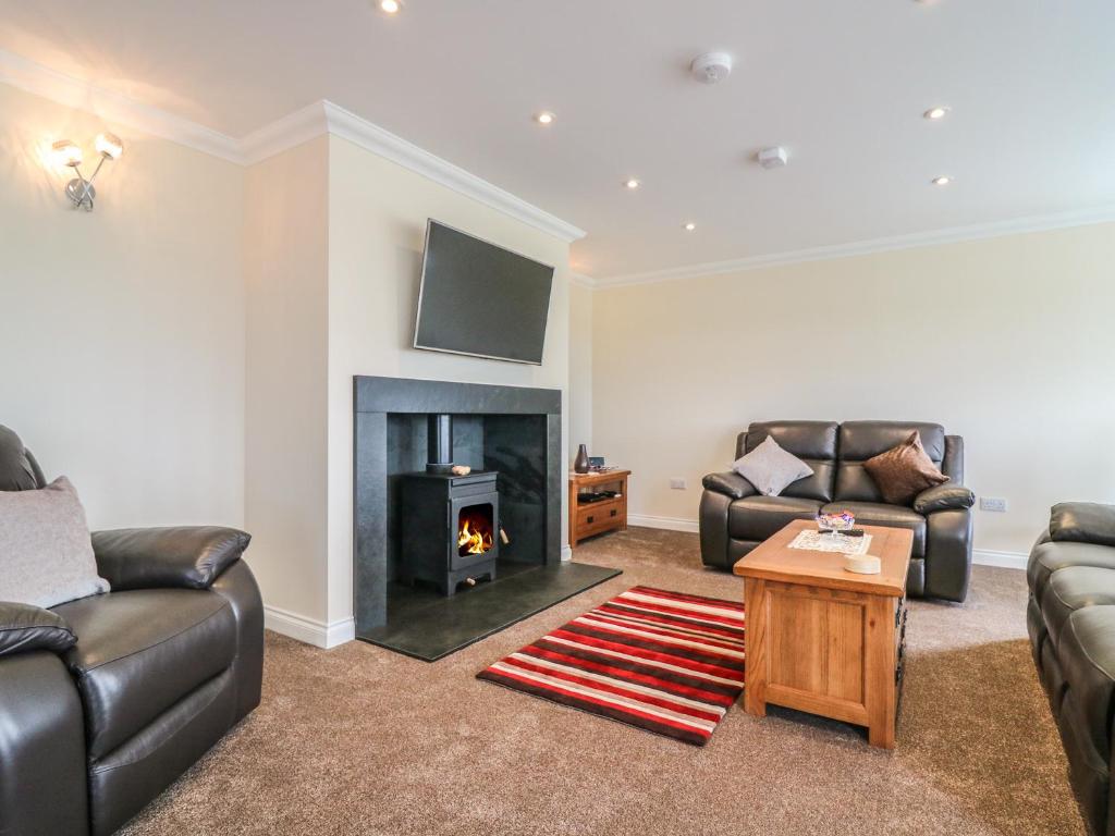 a living room with two couches and a fireplace at Burnside Cottage in Portree