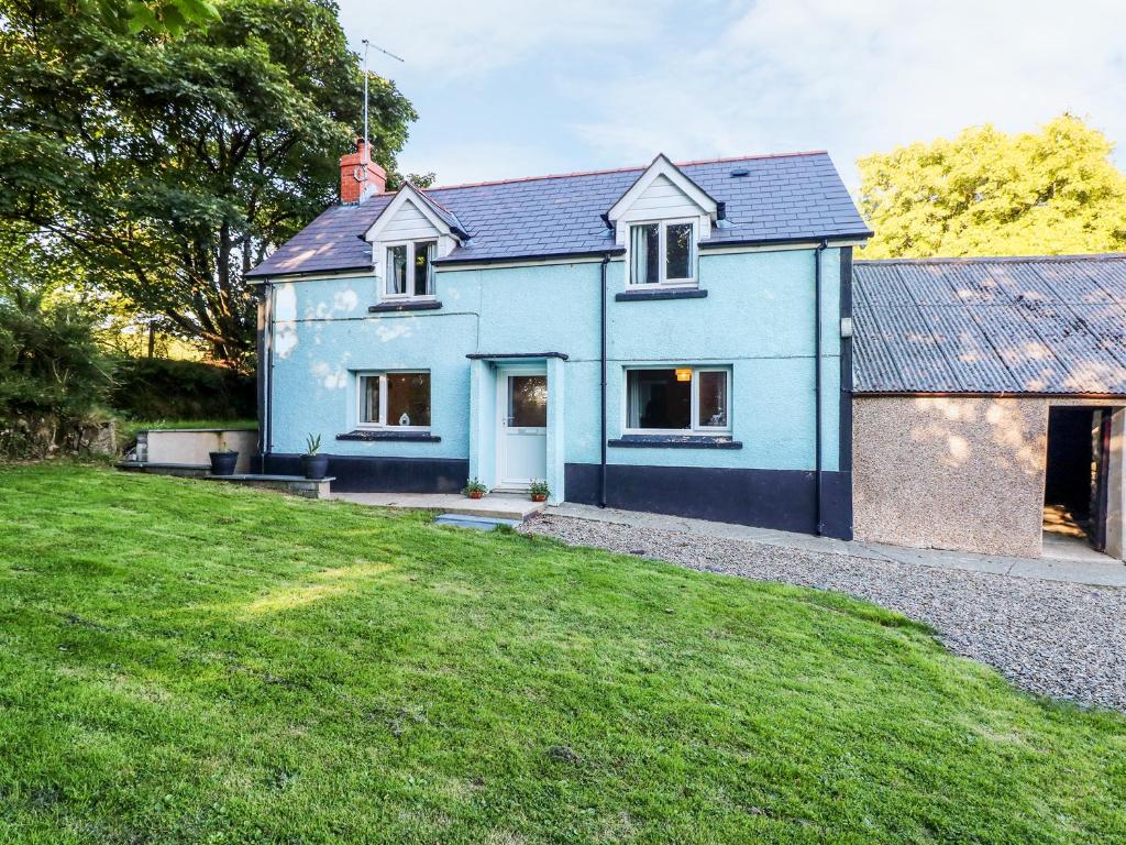 a blue house with a green lawn in front of it at Llygad-yr-Haul in Pontfaen