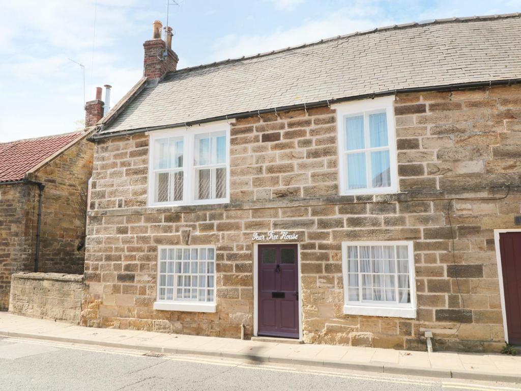 an old stone house with a purple door and white windows at Pear Tree House in Whitby