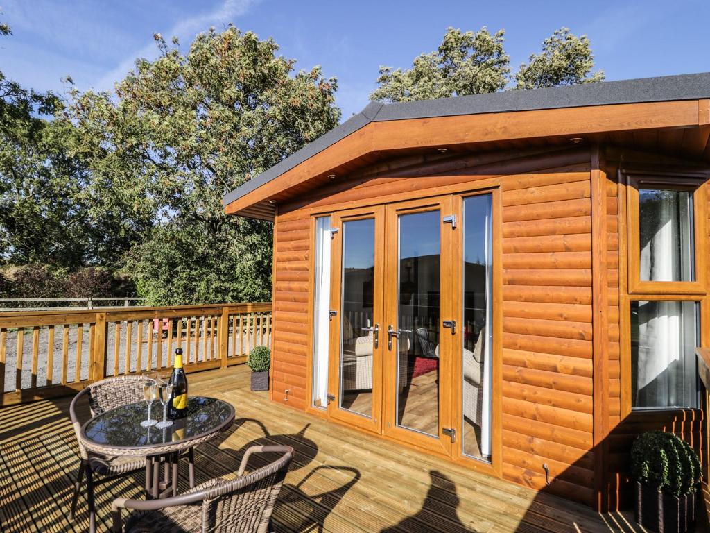 a wooden cabin with a table and chairs on a deck at Beech Tree Lodge in Skirpenbeck