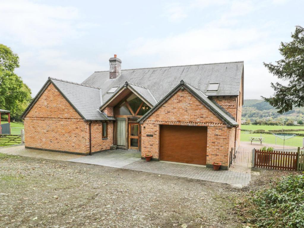 a brick house with a garage at Pentrego Isaf in Meifod