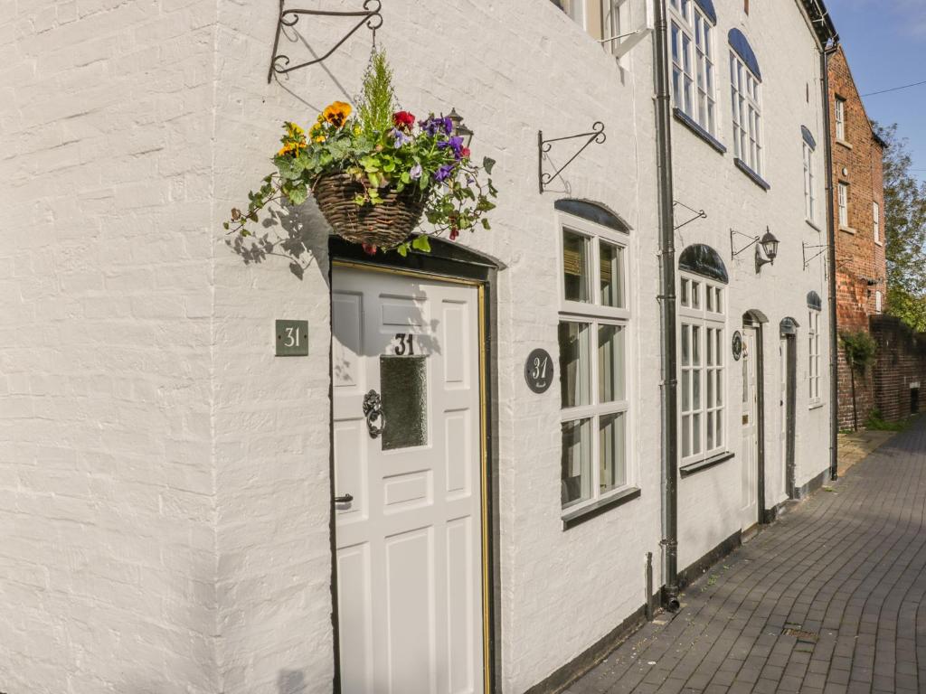 a white building with a door with a basket of flowers on it at 31 Riverside in Bridgnorth