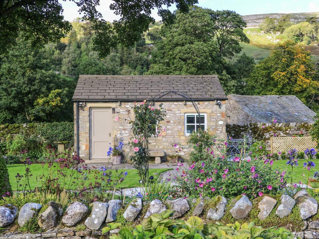a stone cottage in a garden with flowers at The Bothy in Arncliffe