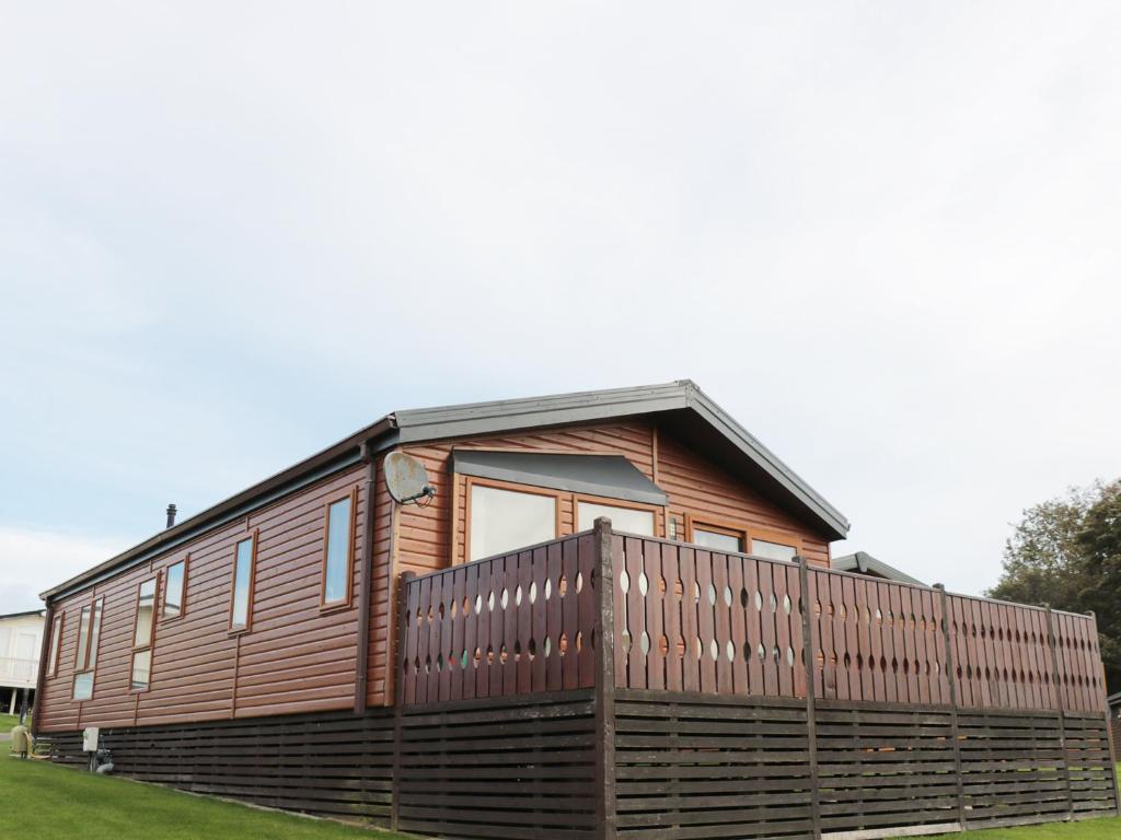 a wooden house with a fence around it at Percy Wood Country Park in Newton on the Moor