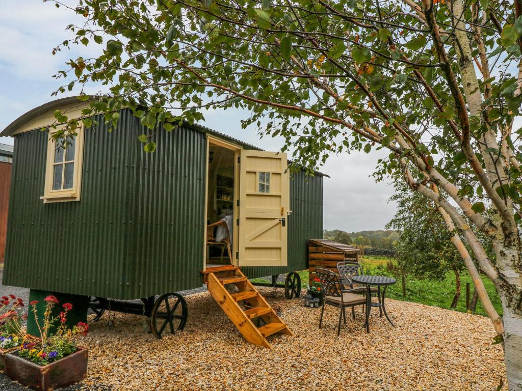 a green tiny house with a table and chairs at Moor Skies in Keighley