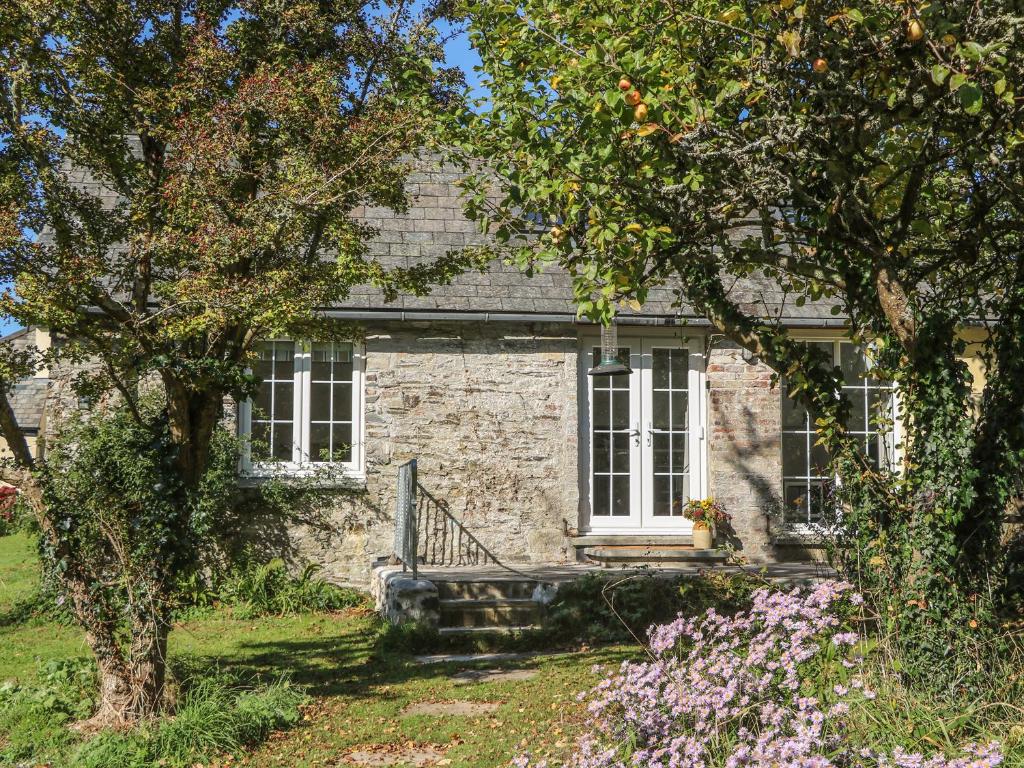 イェルバートンにあるThe Daffodil Shedの白窓と木々のある石造りの家