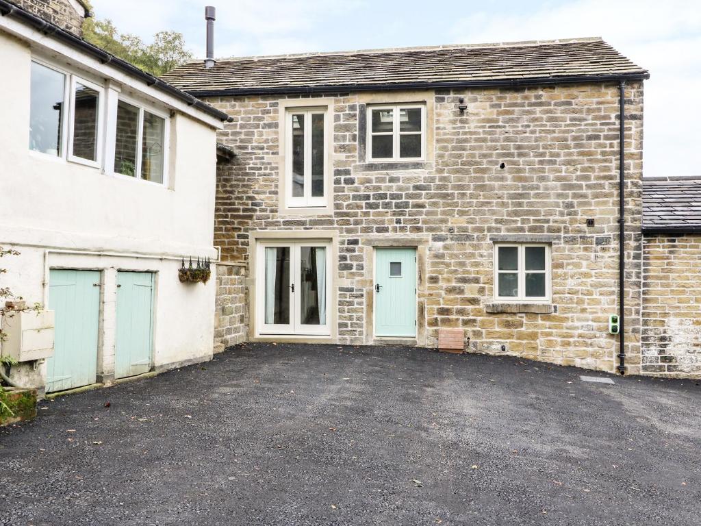 una vieja casa de ladrillo con un estacionamiento en Morgan's Barn en Huddersfield