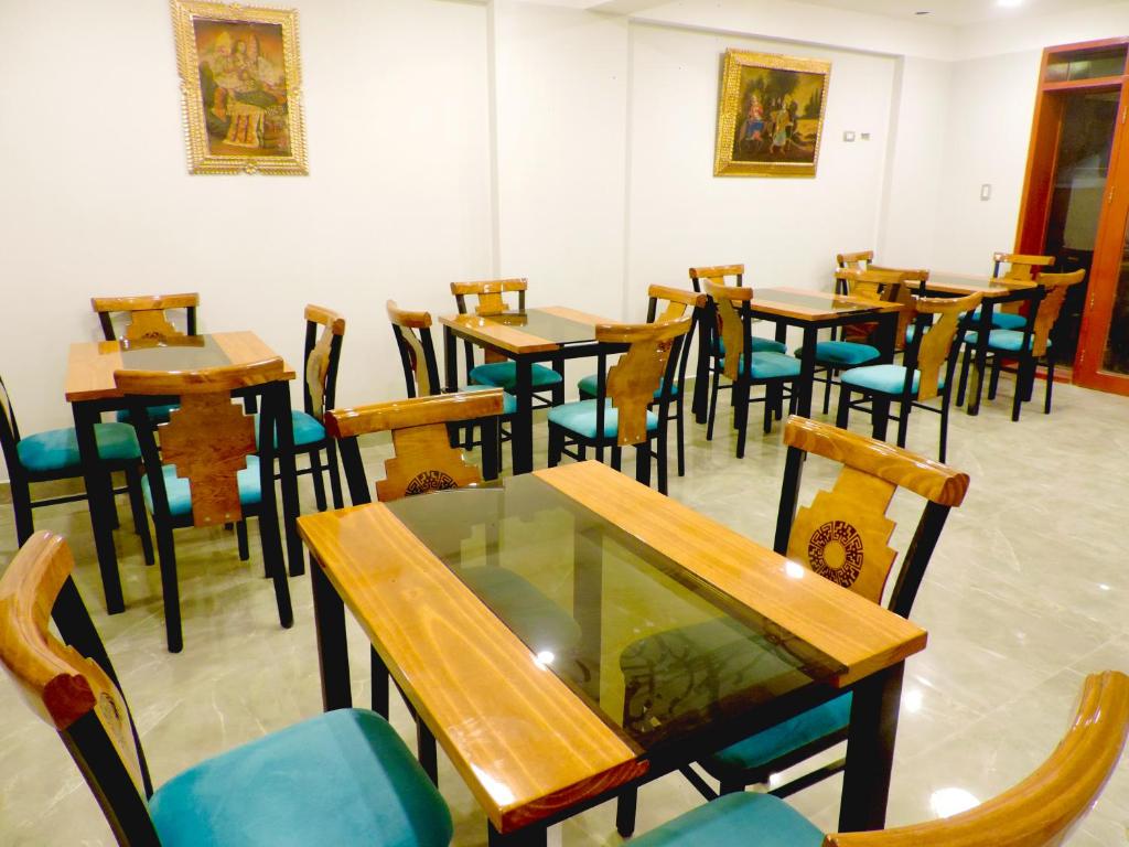 una sala da pranzo con tavoli e sedie in legno di HOTEL LUZ GARDEN a Machu Picchu
