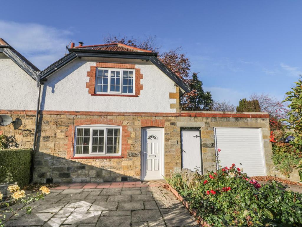 ein Backsteinhaus mit zwei weißen Garagentüren in der Unterkunft Yew Court Cottage in Scarborough