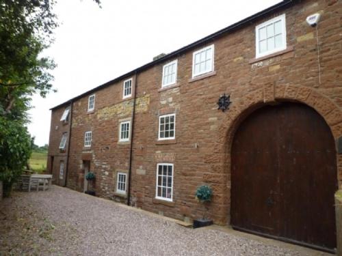 a large brick building with a large garage at Carleton Mill Cottage in Carlisle