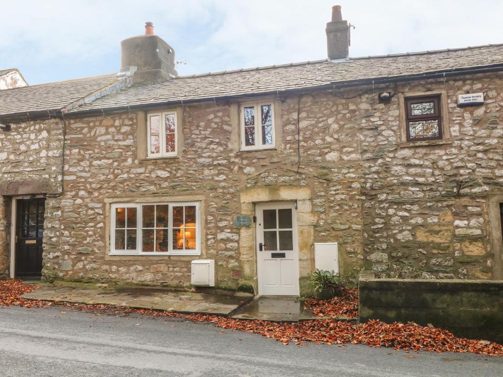 an old stone house with a white door at 2 Storrs Cottages in Carnforth
