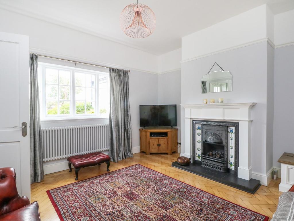 a living room with a fireplace and a tv at Sunlight Soap Cottage in Wirral