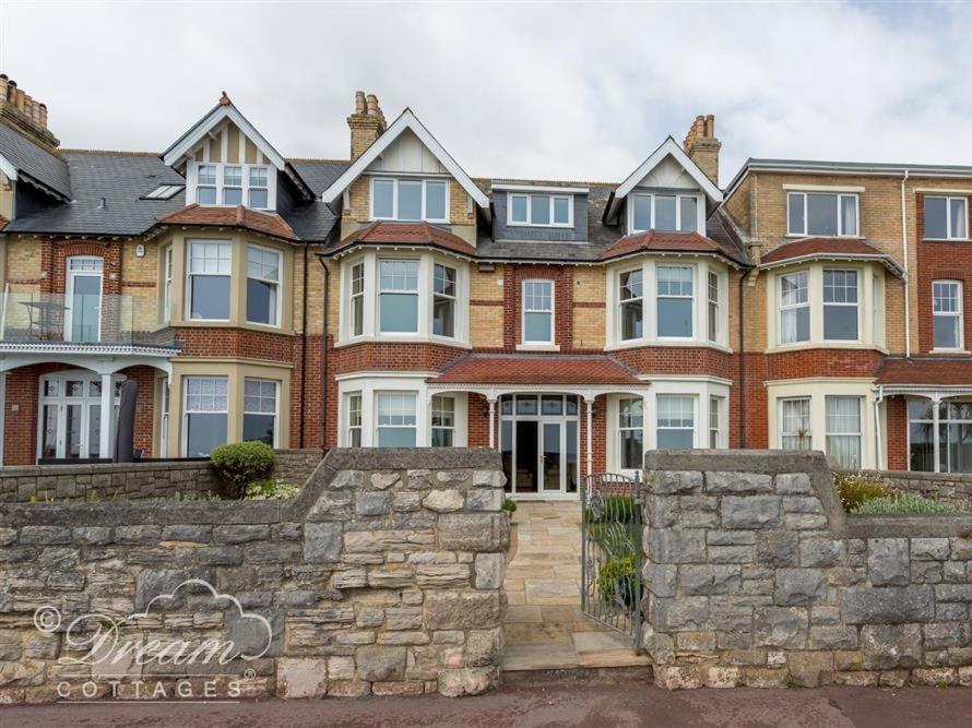 a large brick house with a stone wall at Beach View Apartment 3 in Weymouth