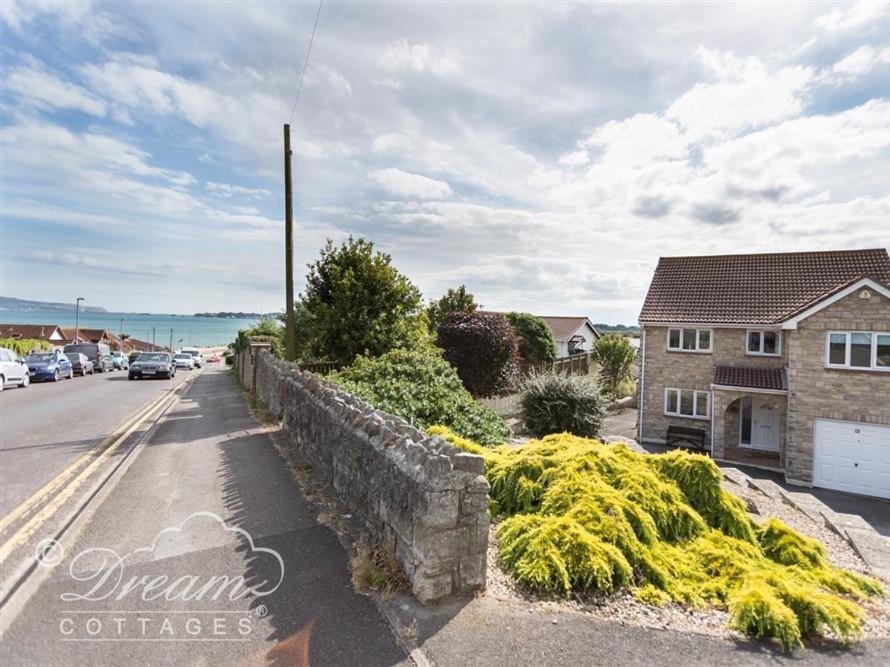 a street with a retaining wall and a house at Bowleaze View in Weymouth