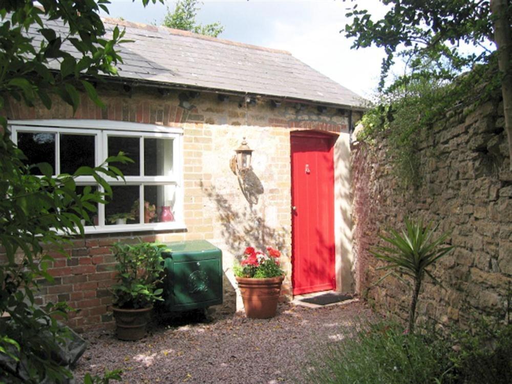 a brick house with a red door and a window at Fountain Cottage in Weymouth