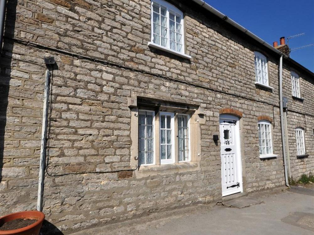 a brick building with a white door and windows at Tavern Way in Corfe Castle