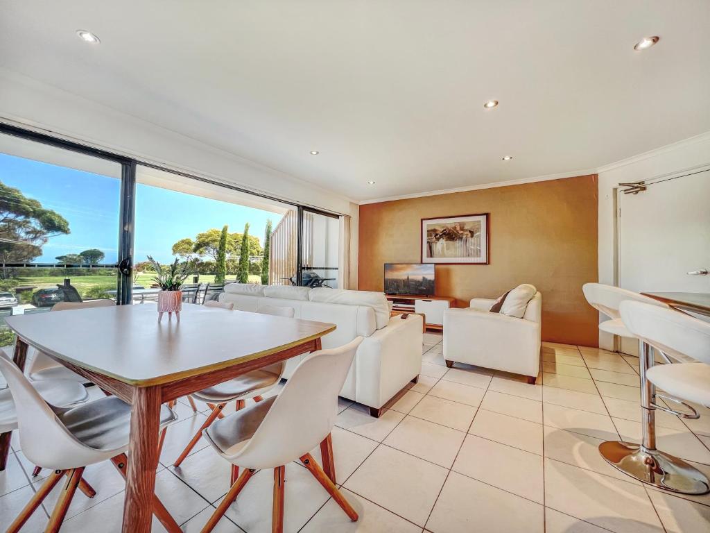 an open living room with a table and chairs at Seachange Apartments Merimbula in Merimbula