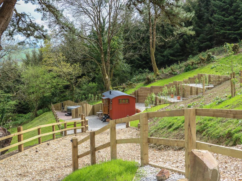 un pequeño tren rojo en un jardín con una valla en Little Silver Owl, en High Bickington