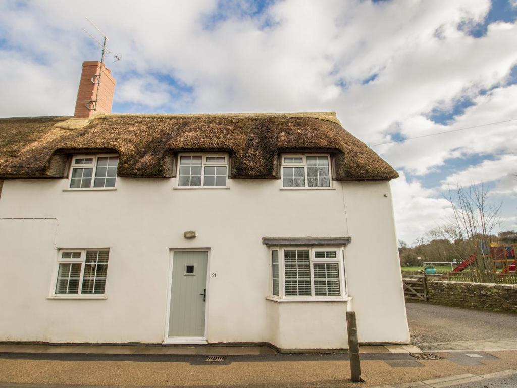 a thatched cottage on the side of the road at Long Barn in Burton Bradstock