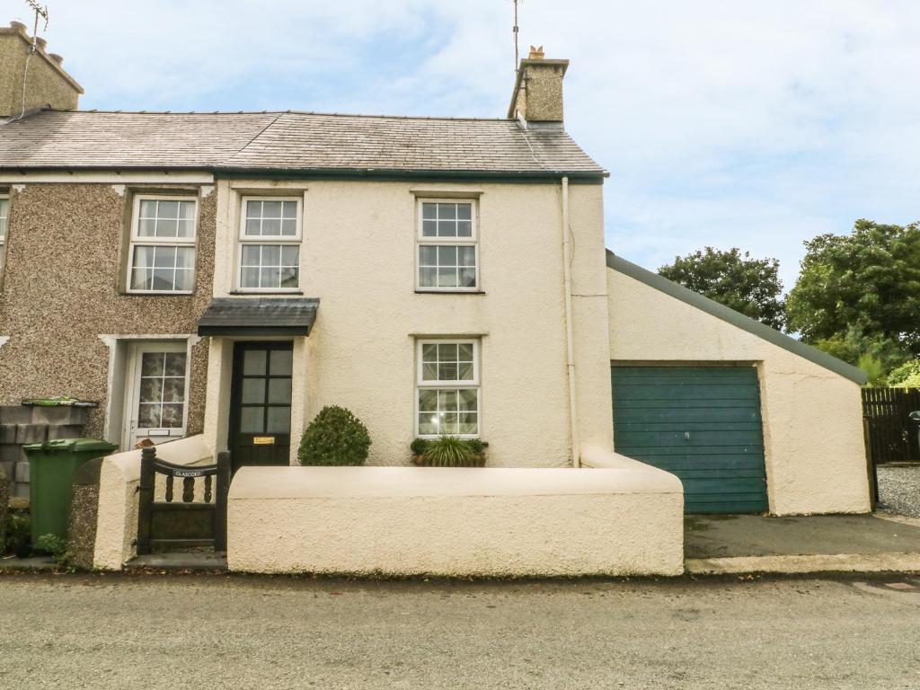 a white house with a blue garage at Glascoed in Pwllheli