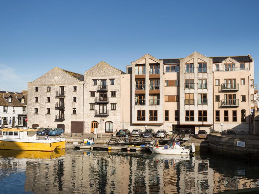 un groupe de bateaux amarrés dans l'eau devant les bâtiments dans l'établissement Harbourside Penthouse, à Weymouth