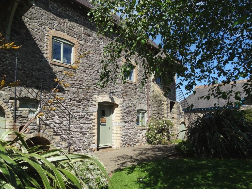 a stone house with a white door and a yard at St Aubyn Cottage in Plymouth