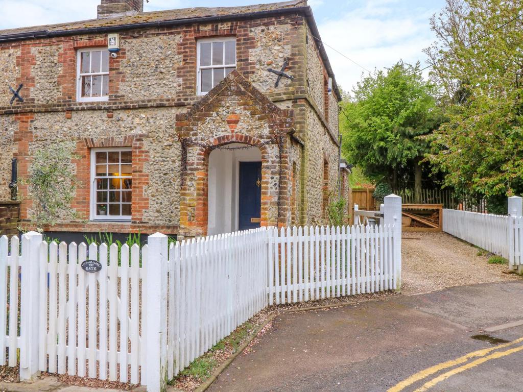 an old brick house with a white picket fence at 3 Station Cottages in Wymondham