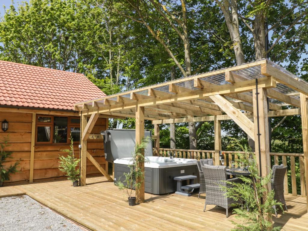 a wooden pergola with a hot tub on a deck at Oak Lodge in Watchet