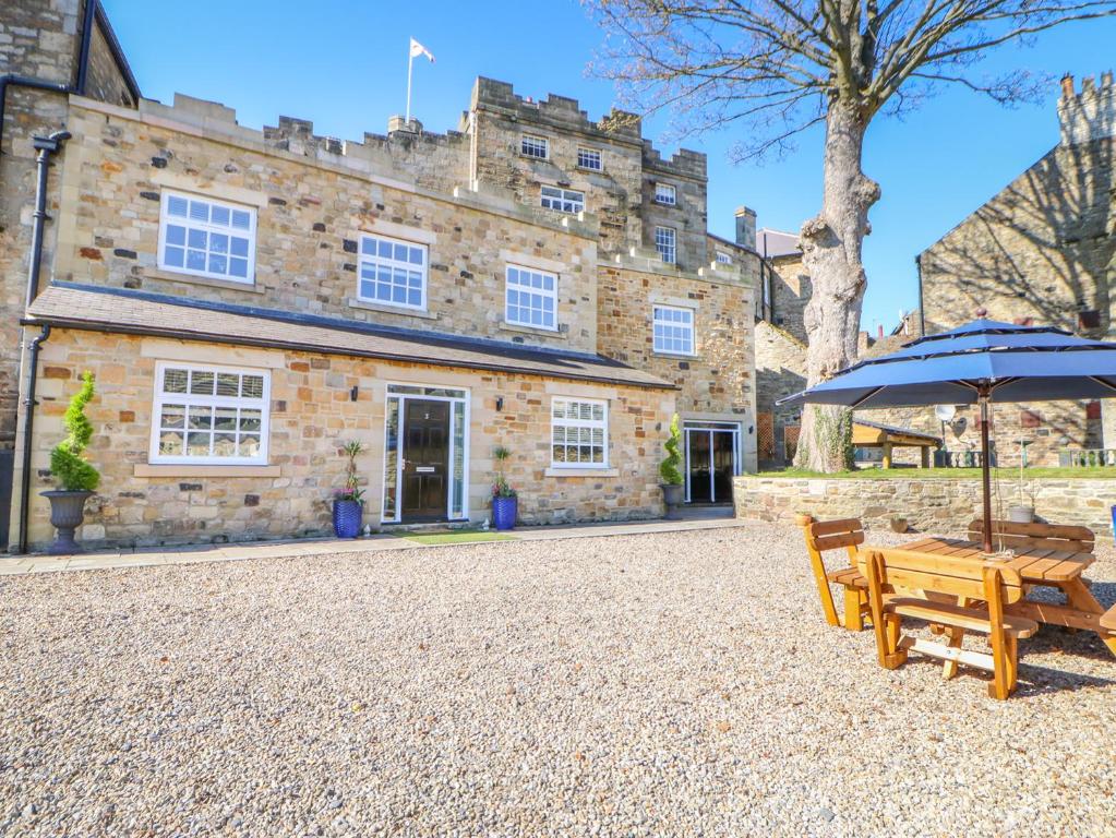 an umbrella and benches in front of a building at Cosy Cave Stanhope Castle in Bishop Auckland