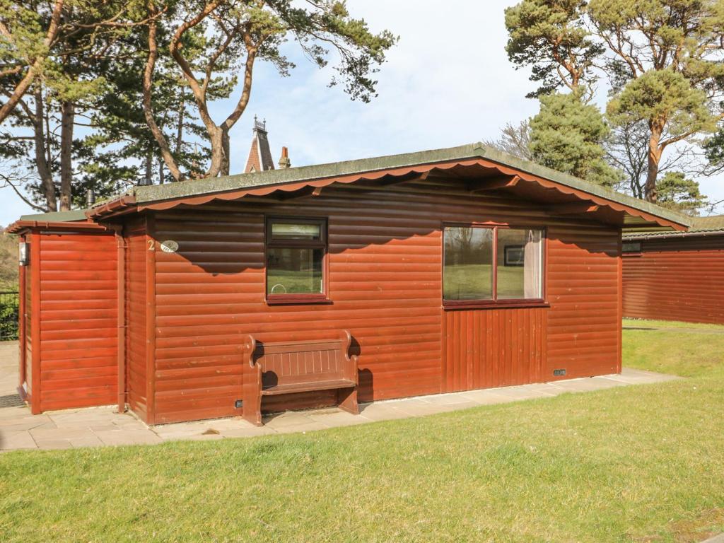 uma pequena cabana de madeira com um banco na relva em Orchid Lodge em Saltburn-by-the-Sea