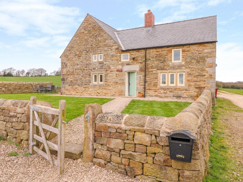 a stone wall in front of a stone house at Woodthorpe Cruck Cottage in Chesterfield