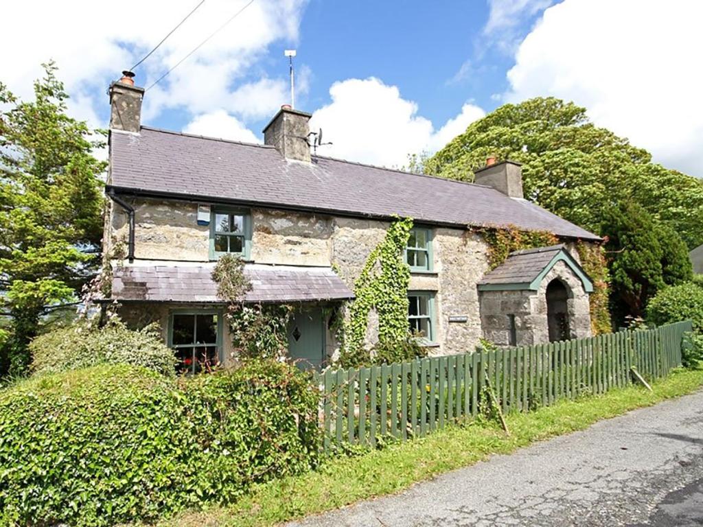 uma velha casa de pedra ao lado de uma estrada em Buck Cottage em Pentraeth