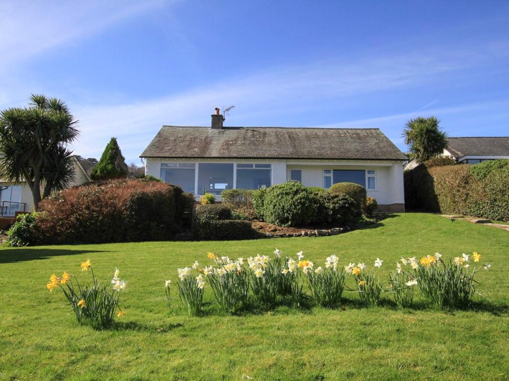 a house on a lawn with flowers in the yard at Camlan in Beaumaris