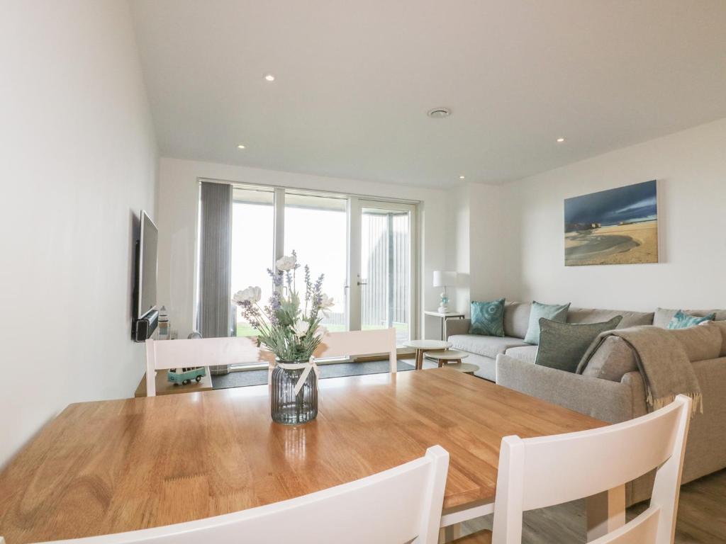 a living room with a table and a couch at Chapel Rock View, The Dunes in Perranporth
