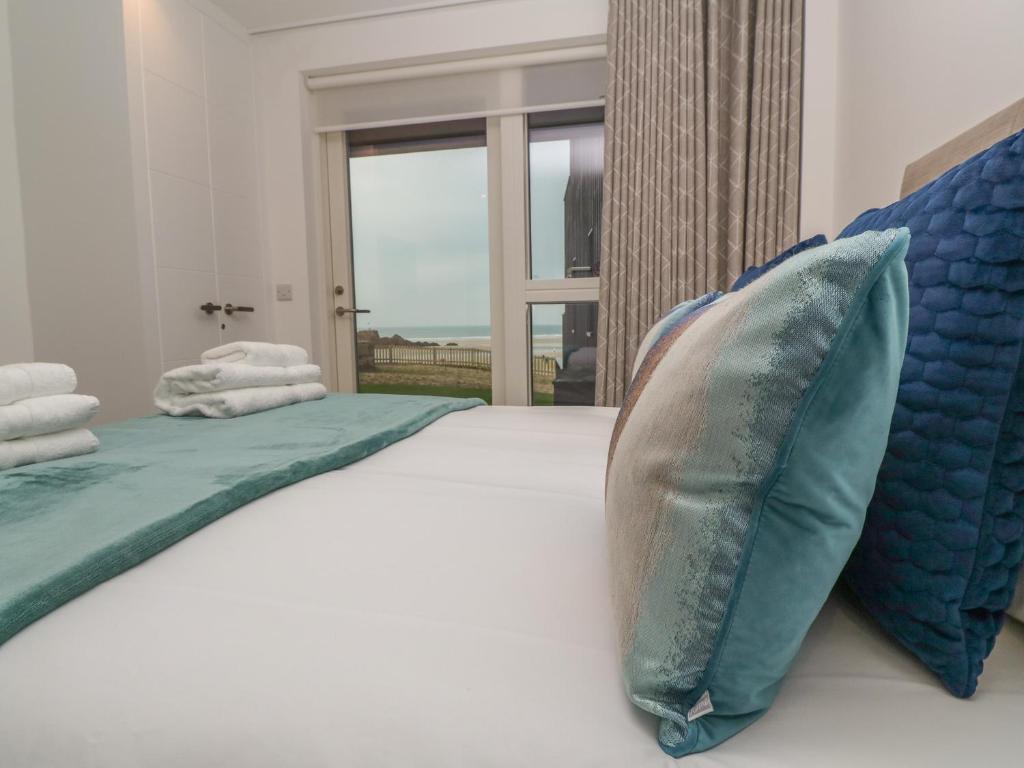 a bedroom with a large bed with blue pillows at Chapel Rock View, The Dunes in Perranporth