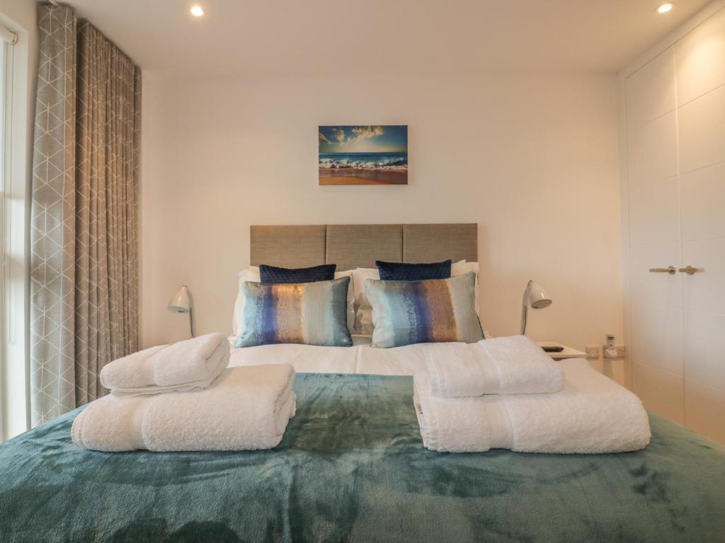 a bedroom with a large bed with white towels on it at Chapel Rock View, The Dunes in Perranporth