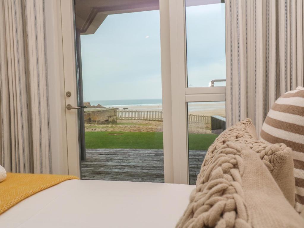 a bedroom with a bed and a view of the ocean at Chapel Rock View, The Dunes in Perranporth