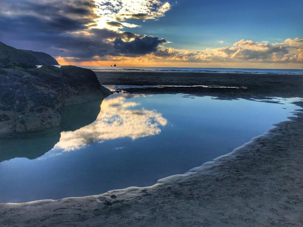 a reflection of the sky in the water on a beach at Chapel Rock View, The Dunes in Perranporth