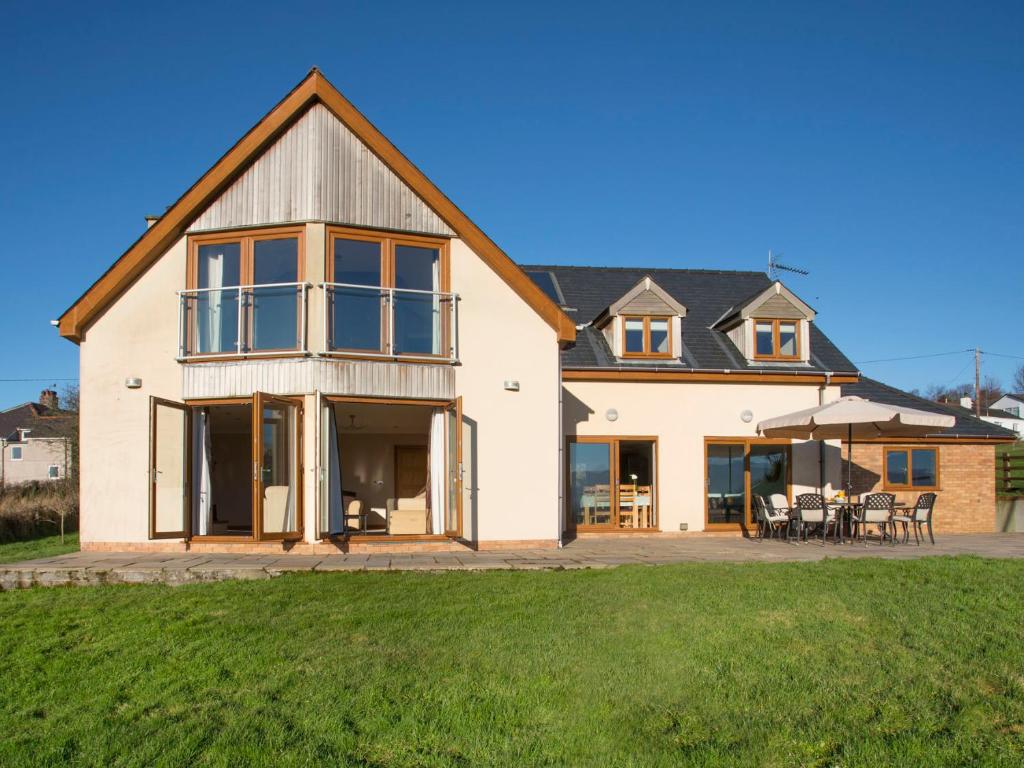 Cette grande maison blanche dispose de grandes fenêtres et d'herbe verte. dans l'établissement Dol Fraint, à Llanfairpwllgwyngyll