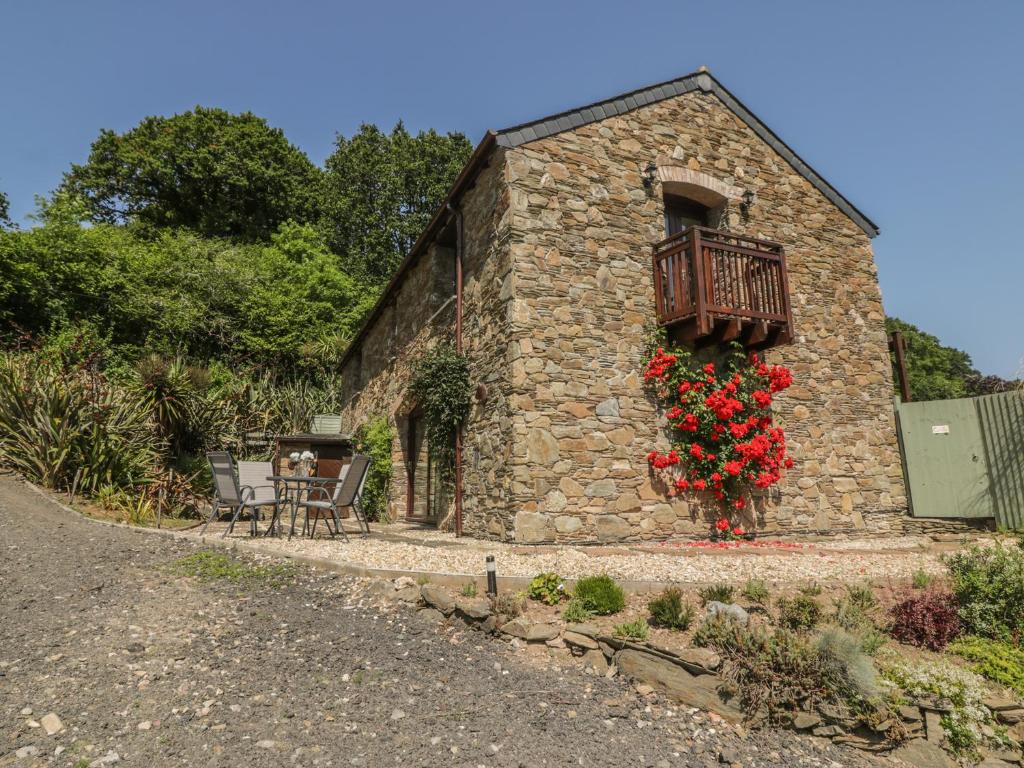 a stone building with a balcony with red flowers on it at Bearscombe in Ivybridge