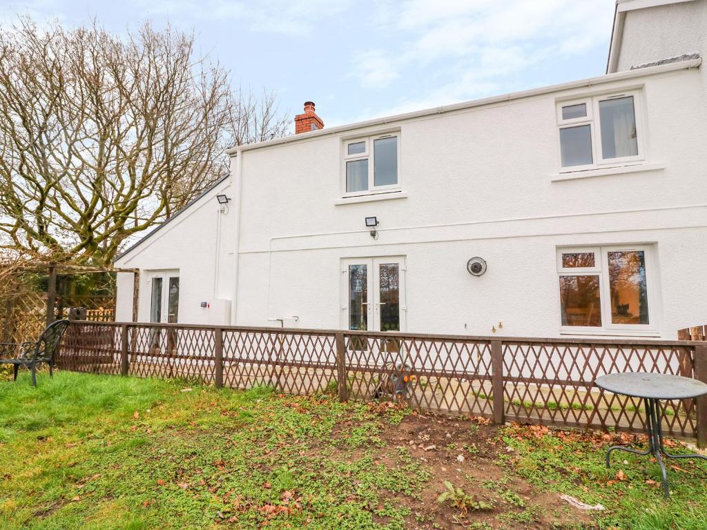 a white house with a fence and a table at Crooked Hill Cottage in Ammanford