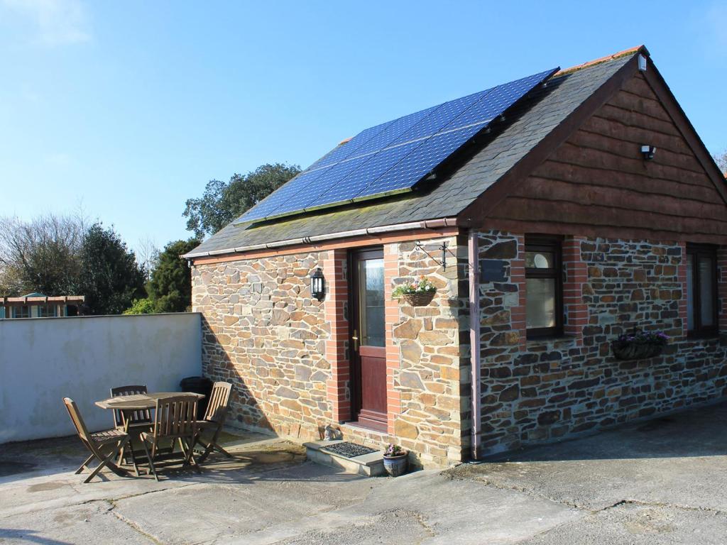 ein kleines Backsteingebäude mit einem Tisch und einer Terrasse in der Unterkunft Little May in Newquay