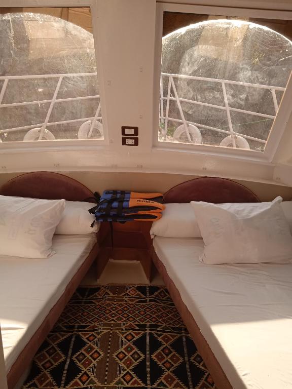 two beds in a room with two windows at Houseboat Hotel and Nile Cruises Zainoba in Nag` el-Ramla