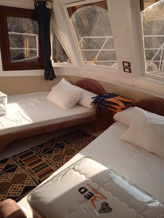 two beds in a room with two windows at Houseboat Hotel and Nile Cruises Zainoba in Nag` el-Ramla