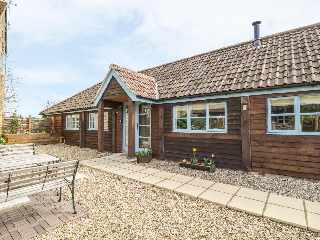 una casa di legno con una panchina di fronte di Shippon Barn a Yeovil